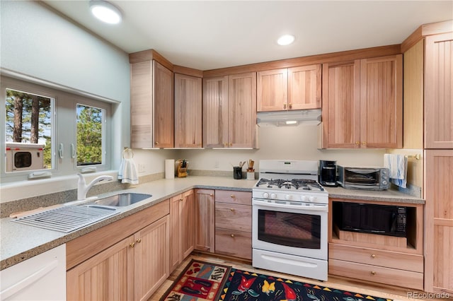 33002 Bobcat Ct, Trinidad, CO 81082 - kitchen featuring white gas stove, under cabinet range hood, light countertops, a sink, and light brown cabinets
