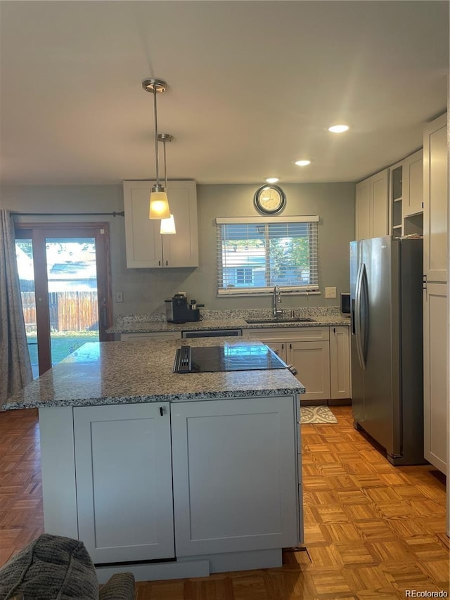 kitchen with plenty of natural light, a center island, stainless steel refrigerator with ice dispenser, and a sink