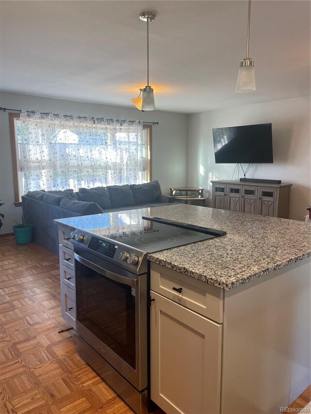 kitchen with a wealth of natural light, open floor plan, stainless steel range with electric cooktop, and light stone countertops