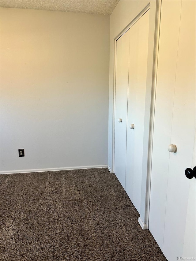 unfurnished bedroom with carpet, baseboards, a closet, and a textured ceiling