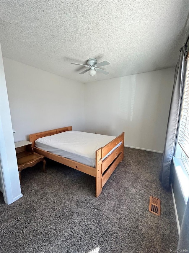 bedroom with visible vents, baseboards, ceiling fan, carpet floors, and a textured ceiling