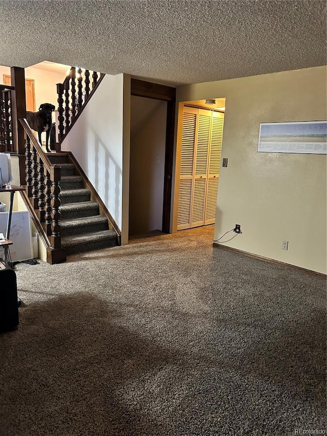 interior space featuring carpet, baseboards, stairs, a textured ceiling, and a textured wall