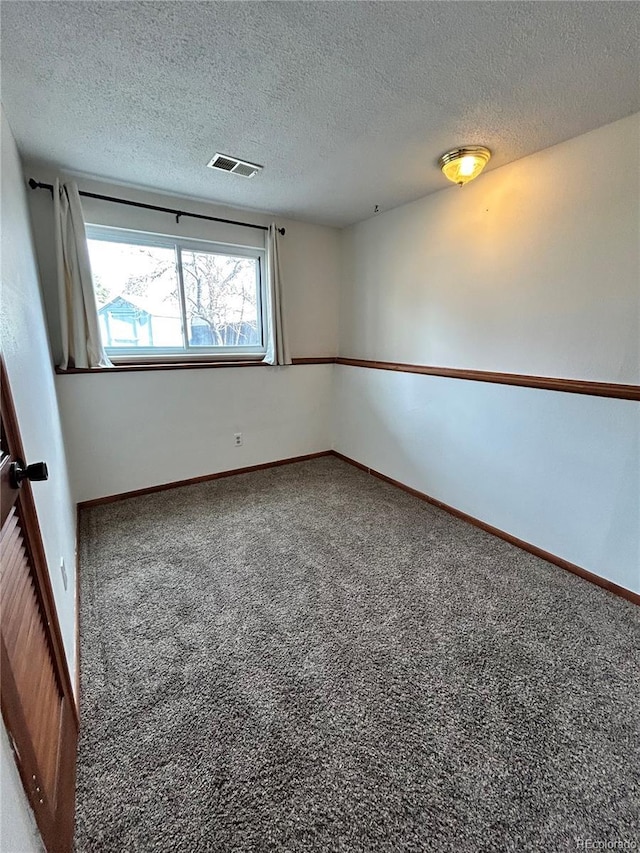 carpeted empty room featuring visible vents, a textured ceiling, and baseboards