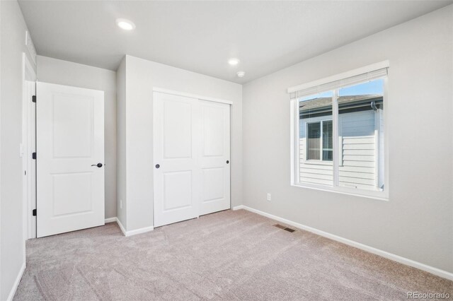 unfurnished bedroom featuring a closet and light carpet