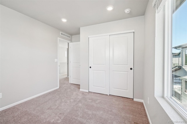 unfurnished bedroom with light carpet and a closet