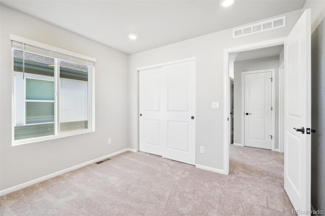 unfurnished bedroom with a closet and light colored carpet