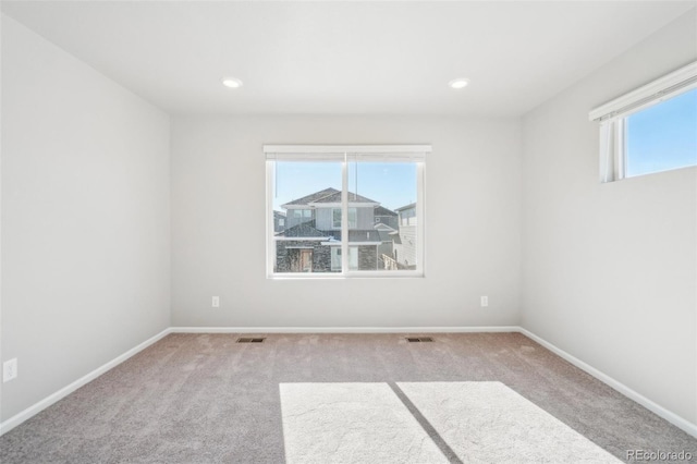 spare room featuring light carpet and a wealth of natural light