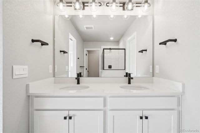 bathroom featuring a shower with shower door and vanity