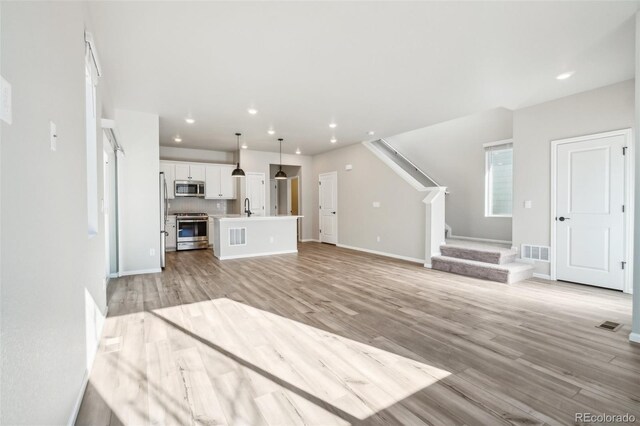 unfurnished living room featuring light hardwood / wood-style floors and sink