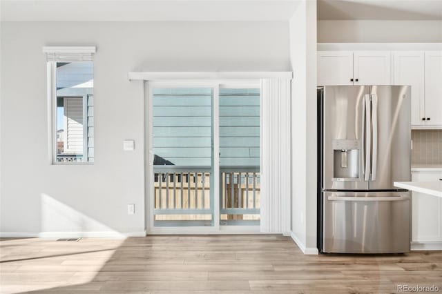 kitchen featuring decorative backsplash, light hardwood / wood-style floors, white cabinetry, and stainless steel fridge with ice dispenser