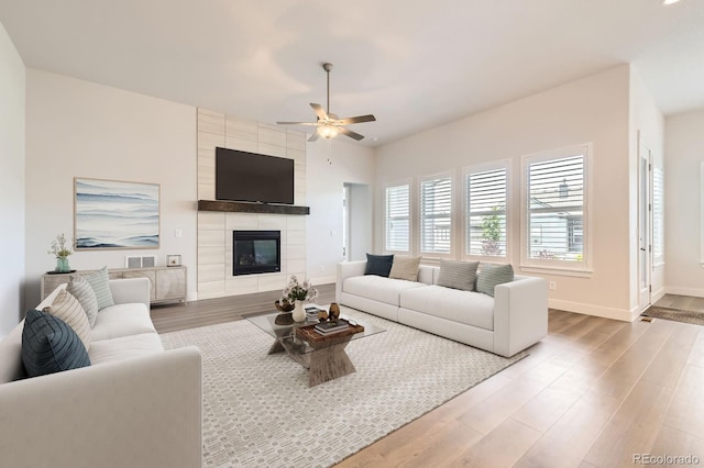 8778 S Quatar St, Aurora, CO 80016 - living area featuring wood finished floors, ceiling fan, and a tiled fireplace