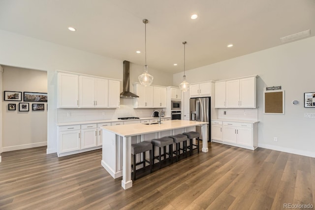 8778 S Quatar St, Aurora, CO 80016 - kitchen featuring wall chimney exhaust hood, stainless steel appliances, white cabinetry, backsplash, and recessed lighting