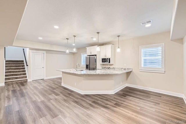 8778 S Quatar St, Aurora, CO 80016 - kitchen featuring stainless steel appliances, a peninsula, wood finished floors, white cabinets, and recessed lighting
