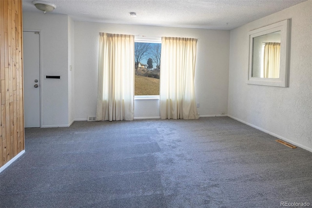 carpeted spare room featuring baseboards, visible vents, and a textured ceiling
