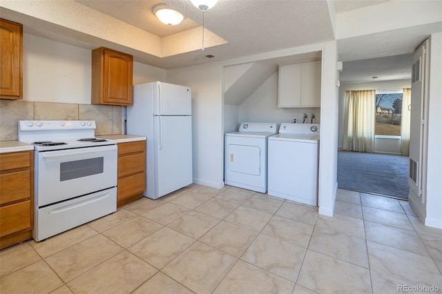 kitchen with brown cabinets, washer and clothes dryer, visible vents, white appliances, and light countertops