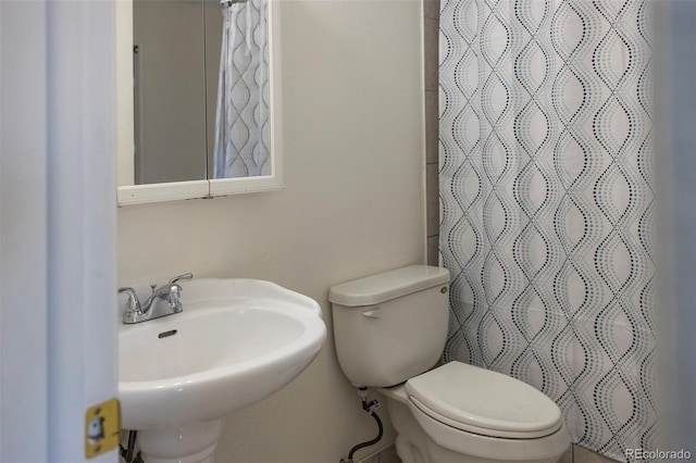 full bathroom with toilet, curtained shower, and a sink