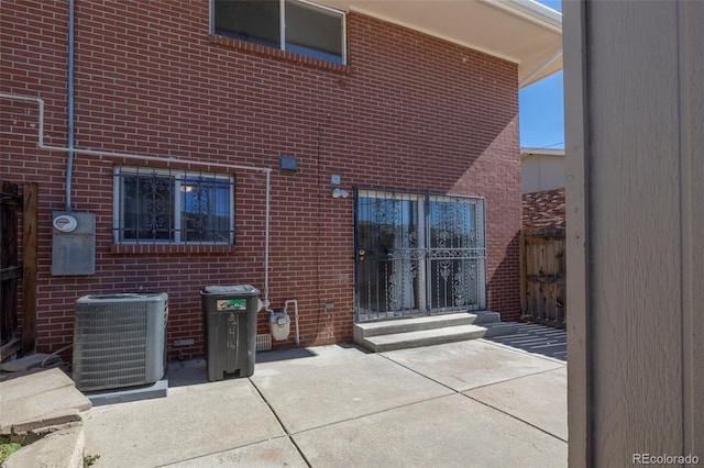 rear view of property featuring central AC unit, a patio area, and brick siding
