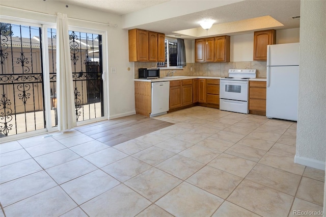 kitchen featuring a sink, white appliances, brown cabinets, light countertops, and light tile patterned floors