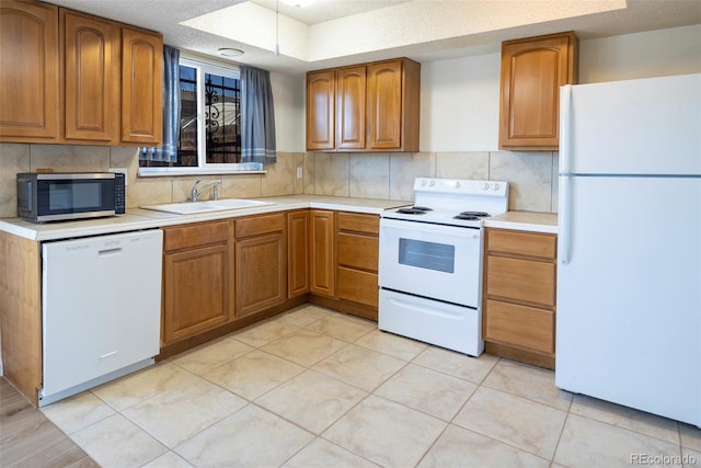 kitchen with white appliances, light countertops, and a sink