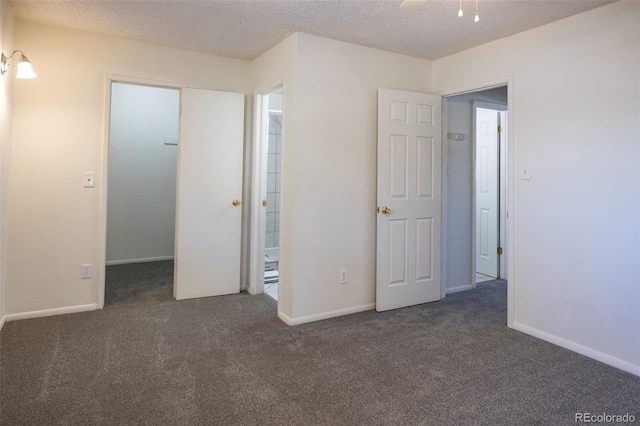 unfurnished bedroom with a textured ceiling, baseboards, a spacious closet, and carpet floors