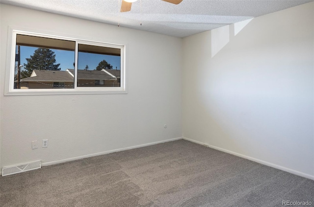 carpeted spare room featuring a textured ceiling, visible vents, baseboards, and a ceiling fan