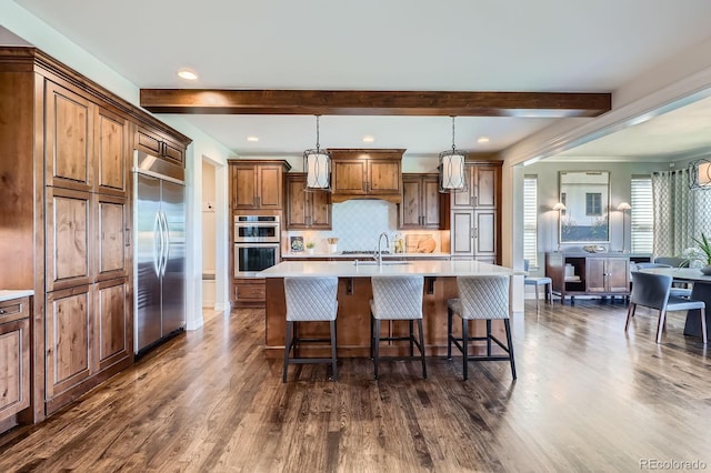 9453 Vista Hill Ln, Lone Tree, CO 80124 - kitchen featuring appliances with stainless steel finishes, dark wood-style floors, beamed ceiling, a kitchen island with sink, and a breakfast bar