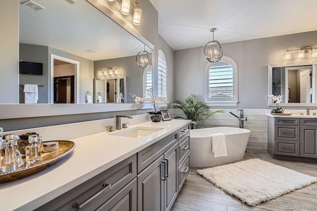 9453 Vista Hill Ln, Lone Tree, CO 80124 - full bathroom featuring vanity, a soaking tub, tile walls, a chandelier, and wood finished floors