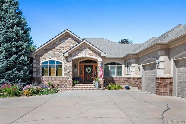 6703 S Yates Ct, Littleton, CO 80128 - view of front facade featuring concrete driveway, a garage, brick siding, stone siding, and roof with shingles