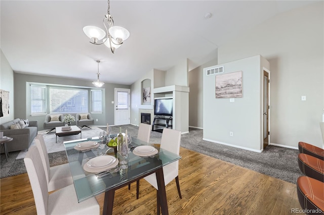 dining room featuring vaulted ceiling, hardwood / wood-style floors, and a notable chandelier