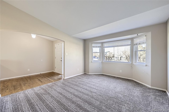 carpeted empty room with vaulted ceiling