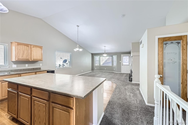 kitchen with sink, decorative light fixtures, a chandelier, a kitchen island, and light colored carpet