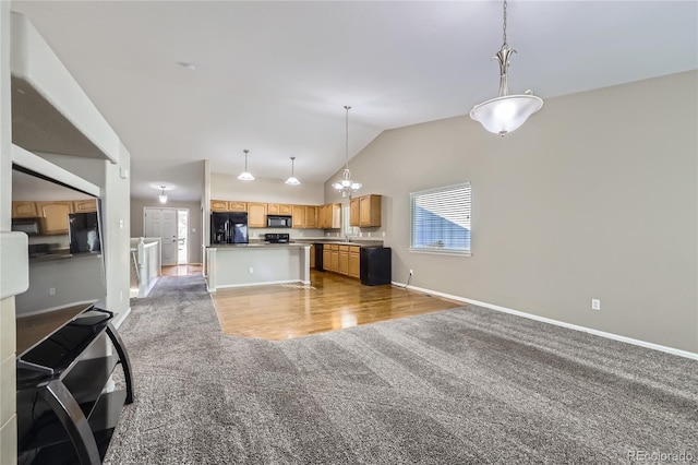 kitchen with hanging light fixtures, light colored carpet, vaulted ceiling, and black appliances