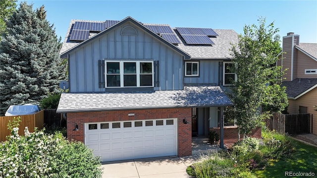 14633 W 69th Pl, Arvada, CO 80004 - view of front of home with board and batten siding, brick siding, an attached garage, solar panels, and concrete driveway