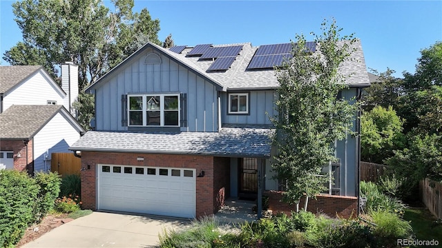 14633 W 69th Pl, Arvada, CO 80004 - view of front facade with board and batten siding, a garage, brick siding, roof mounted solar panels, and roof with shingles