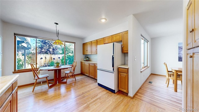 14633 W 69th Pl, Arvada, CO 80004 - kitchen featuring freestanding refrigerator, light countertops, light wood-type flooring, pendant lighting, and brown cabinets