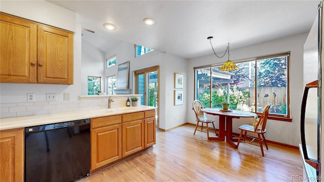 14633 W 69th Pl, Arvada, CO 80004 - kitchen with black dishwasher, light wood finished floors, backsplash, light countertops, and brown cabinetry