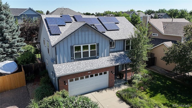 14633 W 69th Pl, Arvada, CO 80004 - view of front of property with board and batten siding, brick siding, concrete driveway, a garage, and roof mounted solar panels
