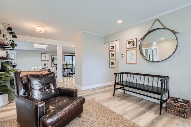 sitting room with light wood-type flooring and crown molding