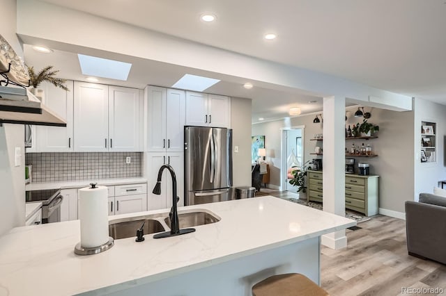 kitchen with kitchen peninsula, light stone counters, white cabinets, and stainless steel appliances