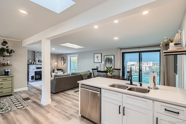 kitchen with light stone countertops, white cabinetry, sink, and stainless steel dishwasher