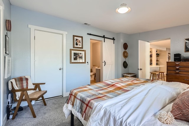 bedroom with carpet, a barn door, and ensuite bathroom