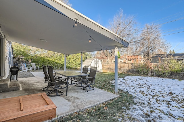 yard covered in snow featuring a shed and a patio area