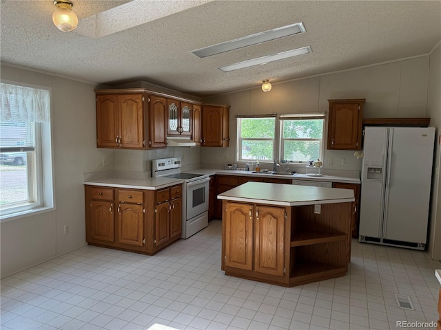 kitchen featuring lofted ceiling with skylight, white appliances, a textured ceiling, and a kitchen island