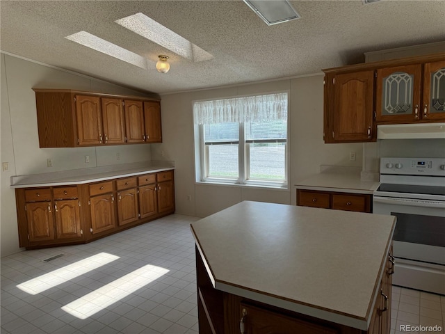 kitchen with white range with electric cooktop, vaulted ceiling with skylight, and a textured ceiling