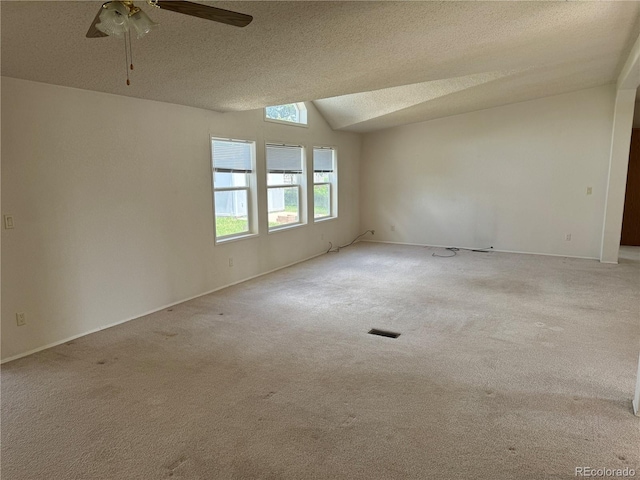 spare room with vaulted ceiling, ceiling fan, a textured ceiling, and light carpet