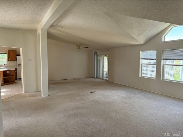 carpeted spare room with a textured ceiling, ceiling fan, a wealth of natural light, and lofted ceiling