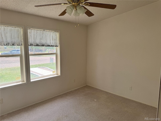 carpeted spare room with a textured ceiling and ceiling fan