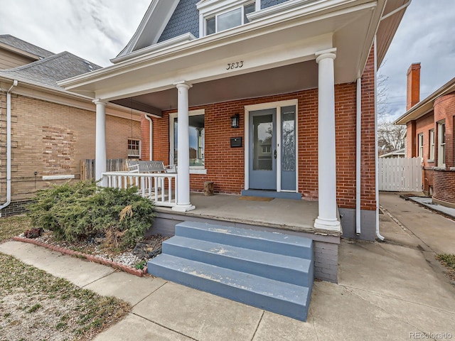 view of exterior entry with covered porch and brick siding