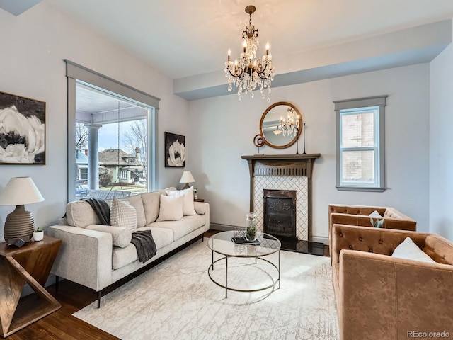 living room featuring a chandelier, a tile fireplace, wood finished floors, and baseboards