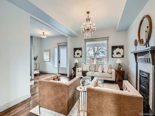 living room with an inviting chandelier, a fireplace, baseboards, and wood finished floors